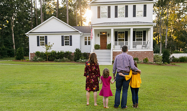 Family standing in front of house